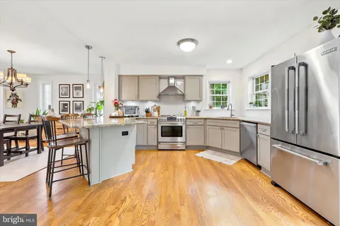 a kitchen with stainless steel appliances a sink a stove a refrigerator cabinets and dining table