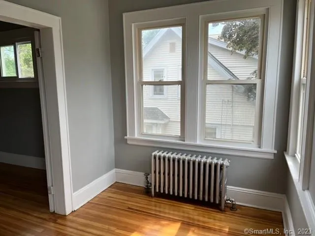 a view of a bedroom with wooden floor and a window