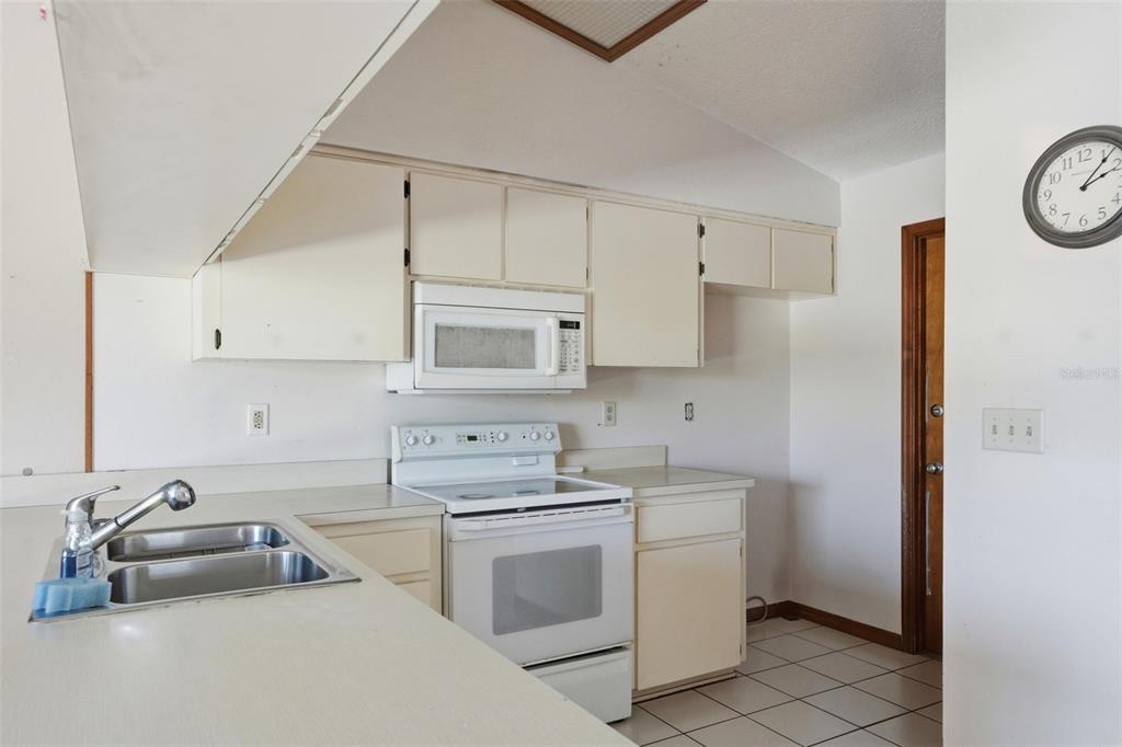7443 Wabash Trail Spring Hill, FL 34606 - Photo 11 of 40 a kitchen with white cabinets and white appliances