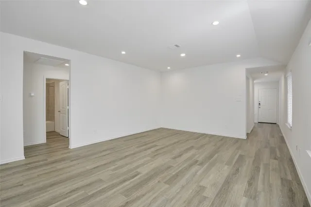 a view of an empty room with wooden floor and closet