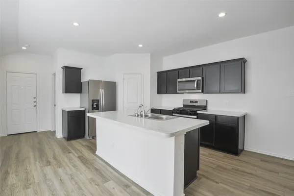 a kitchen with a sink a counter top space stainless steel appliances and cabinets