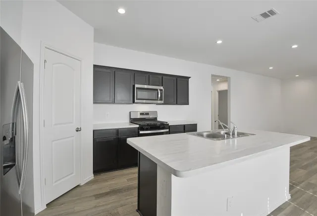 a kitchen with a sink a microwave a refrigerator and cabinets