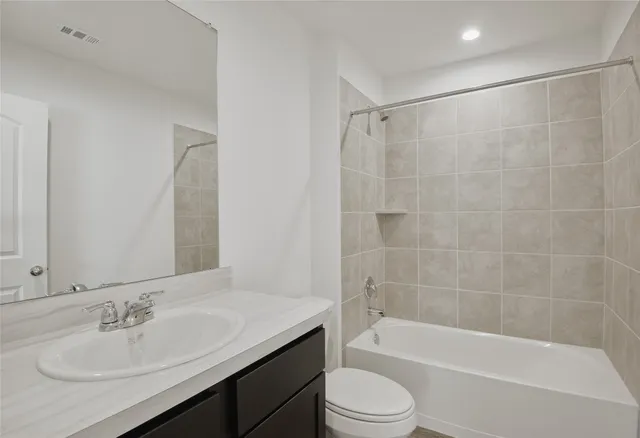 a bathroom with a bathtub shower sink vanity and toilet