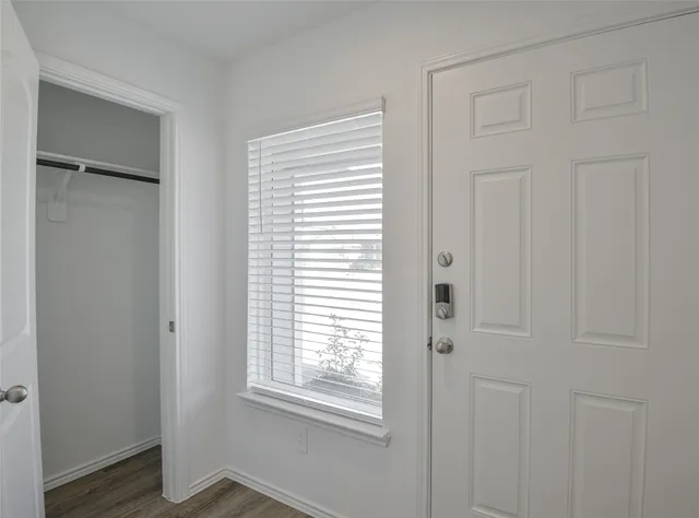 a view of an empty room with wooden floor and a window