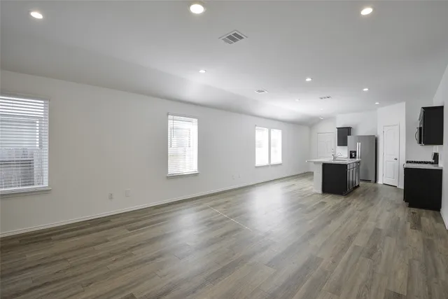 an empty room with wooden floor and windows