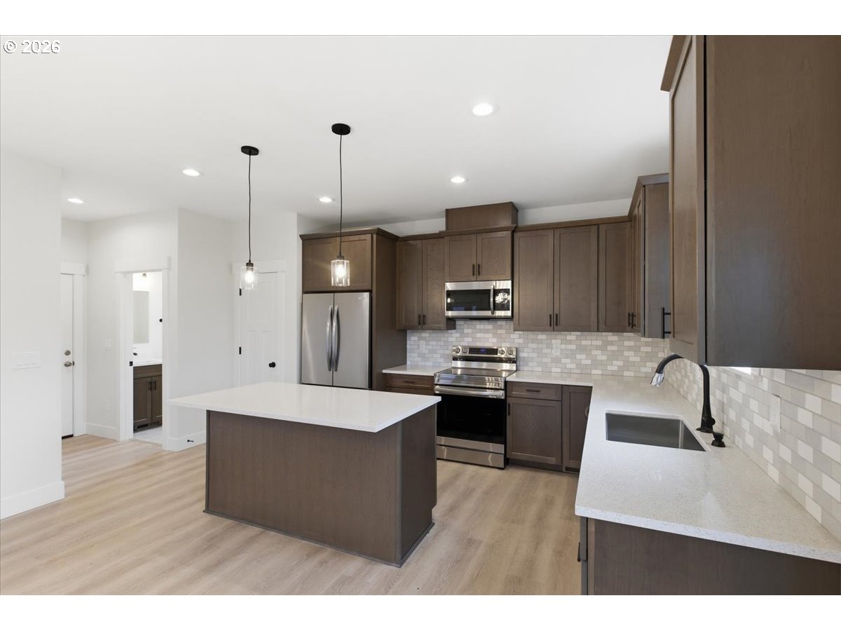 3191 Northwest 23rd Avenue Albany, OR 97321 - Photo 12 of 47 a large kitchen with stainless steel appliances kitchen island granite countertop a sink a stove and a wooden floors