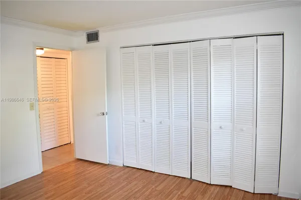 an empty room with wooden floor and windows with curtains