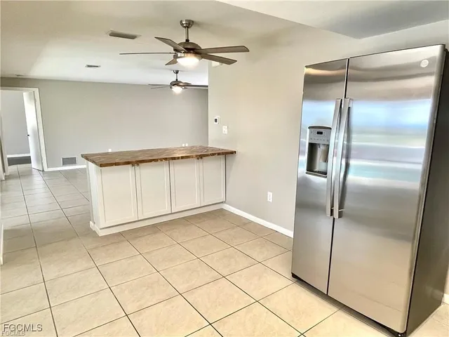 a view of a refrigerator in kitchen and an empty room