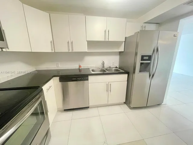 a kitchen with a refrigerator sink and cabinets
