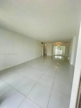 an empty room with chandelier fan and windows