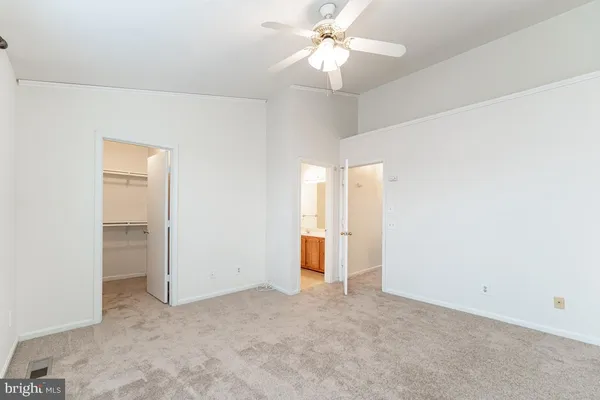 an empty room with closet and a ceiling fan
