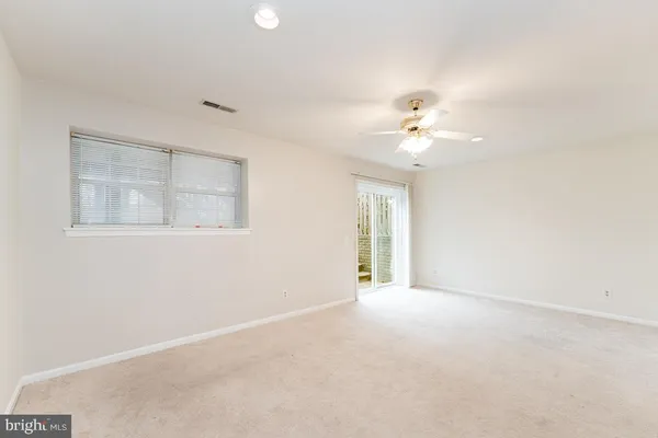 an empty room with a chandelier fan and windows