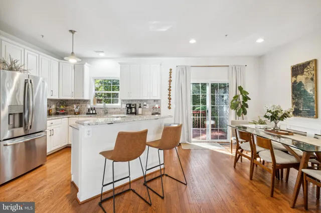 a kitchen with stainless steel appliances granite countertop a refrigerator a stove top oven a sink dishwasher and white cabinets with wooden floor