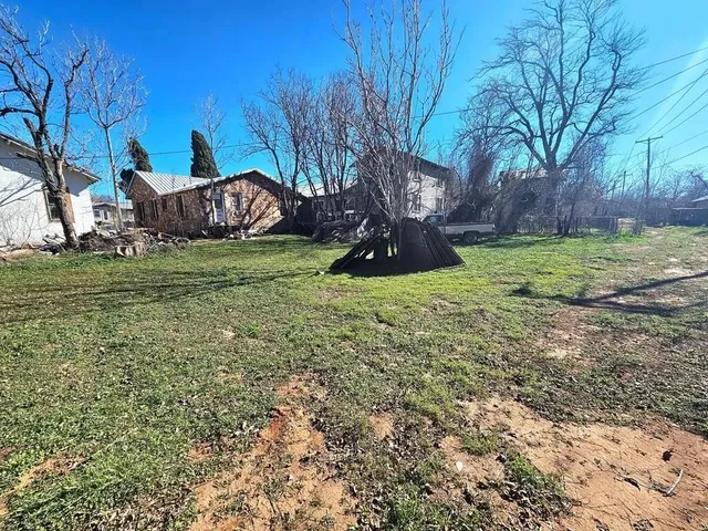 a view of a backyard with table and chairs potted plants and large tree