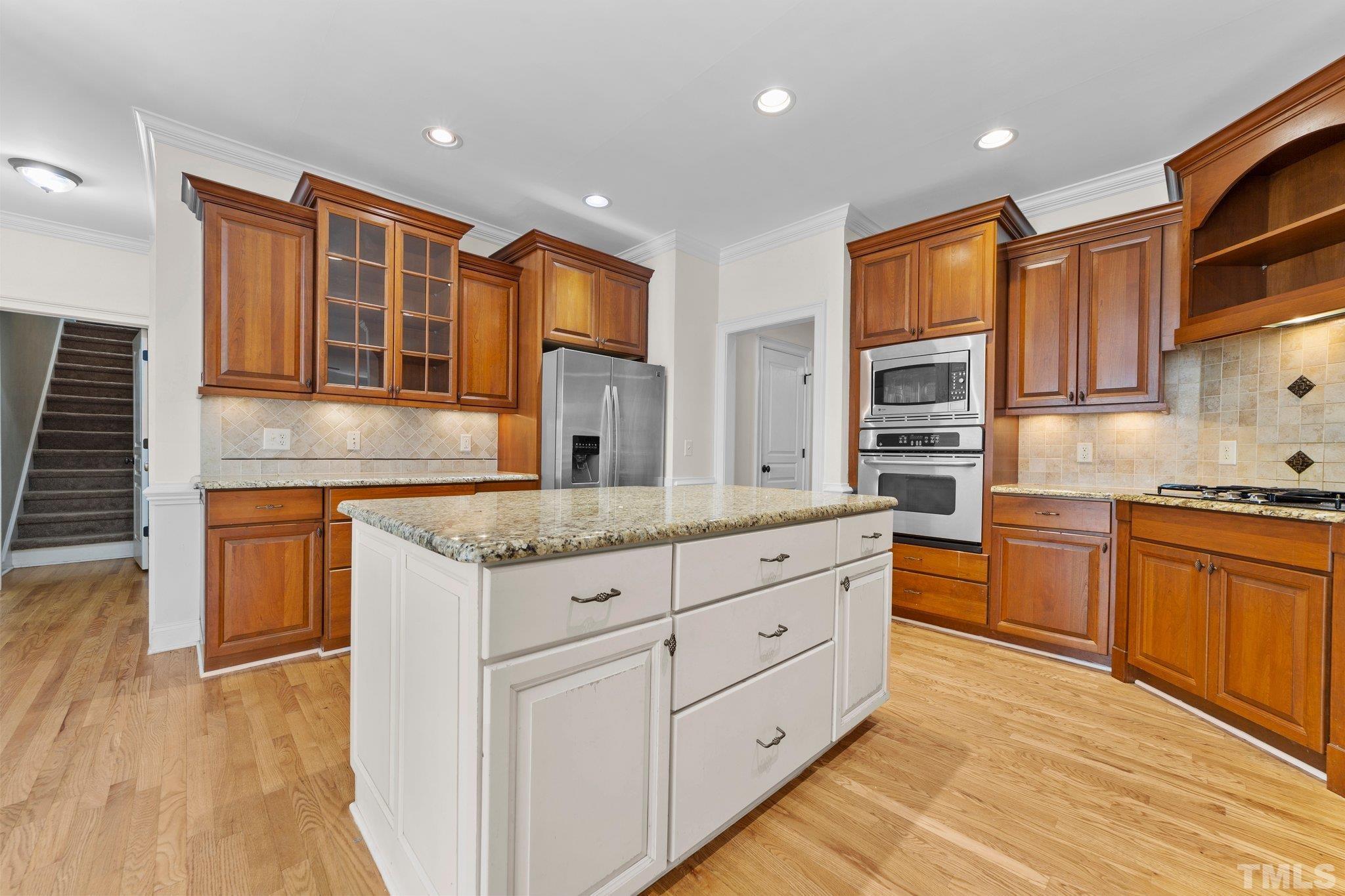 4012 Grandbridge Drive Apex, NC 27539 - Photo 24 of 51 a kitchen with granite countertop kitchen island wooden cabinets and stainless steel appliances