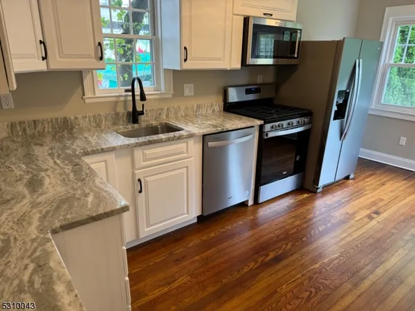 a kitchen with stainless steel appliances granite countertop a stove a sink and a microwave