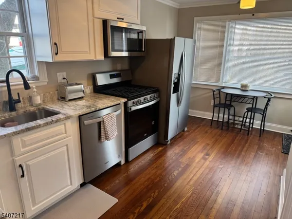 a kitchen with stainless steel appliances wooden floors and wooden cabinets