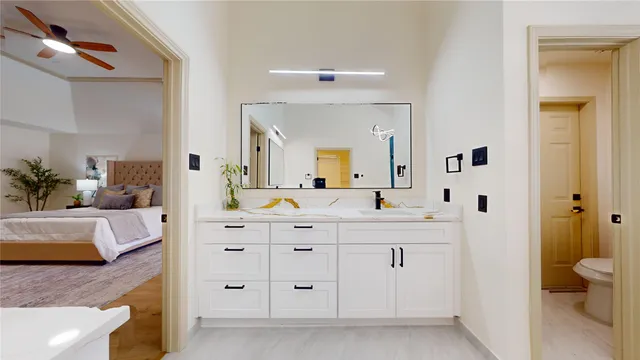 a bedroom with a large bed and a chandelier fan