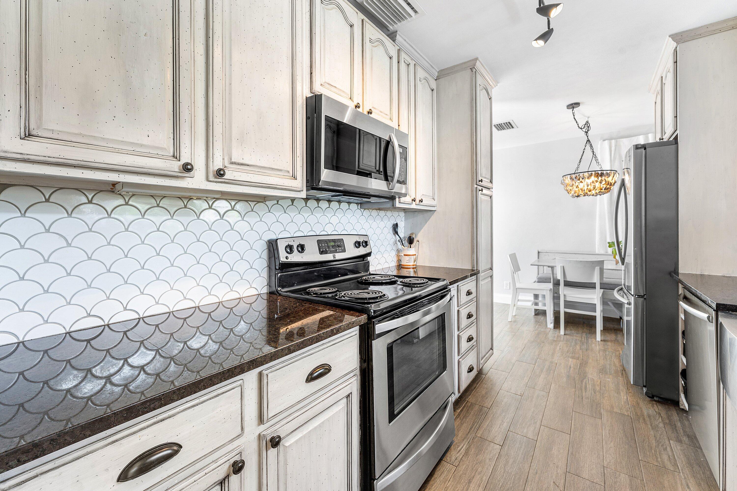 817 Buttonwood Road North Palm Beach, FL 33408 - Photo 11 of 39 a kitchen with stainless steel appliances granite countertop a stove and a wooden floors