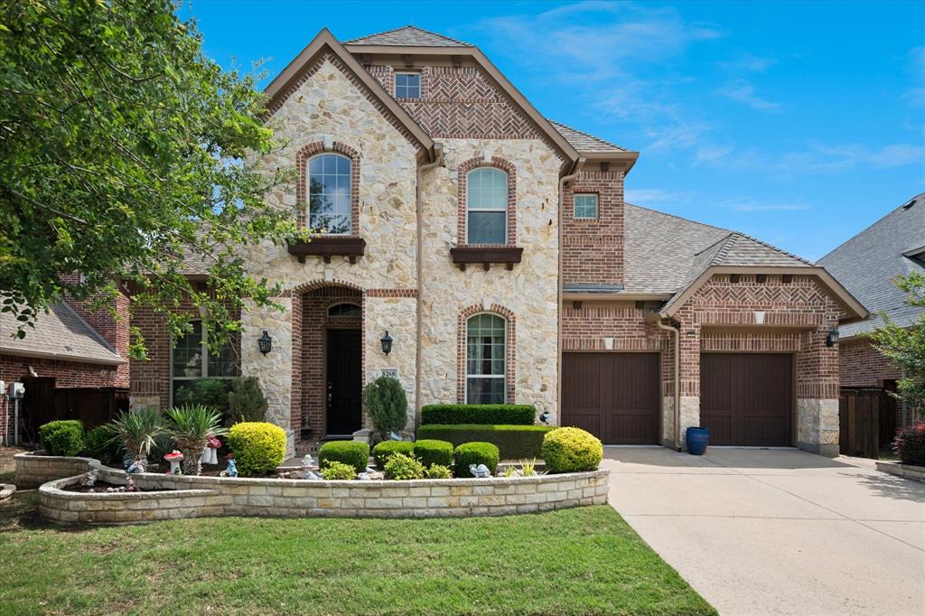 Stone and brick exterior with arched windows, a two-car garage, and a concrete driveway