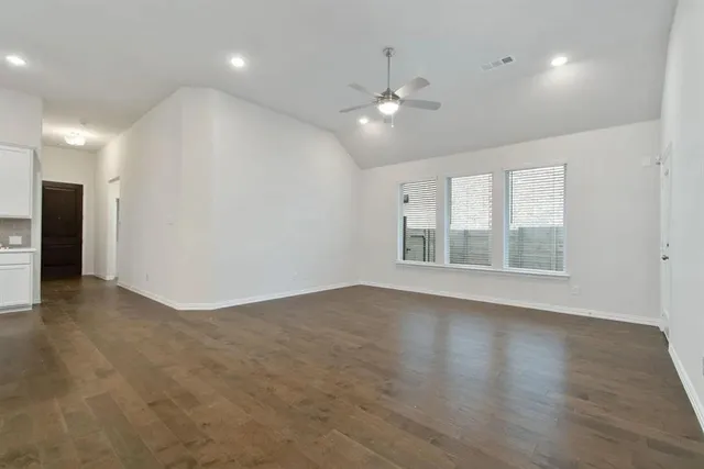 a view of an empty room with a window and wooden floor
