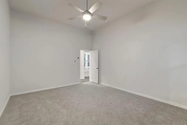 an empty room with chandelier fan and windows