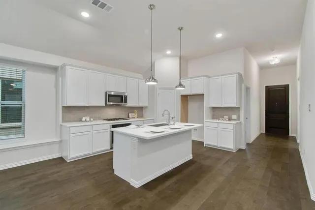 a kitchen with white cabinets and stainless steel appliances