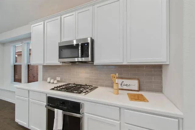 a kitchen with white cabinets and black appliances