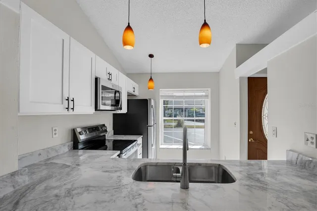 a kitchen with stainless steel appliances granite countertop a sink and a refrigerator