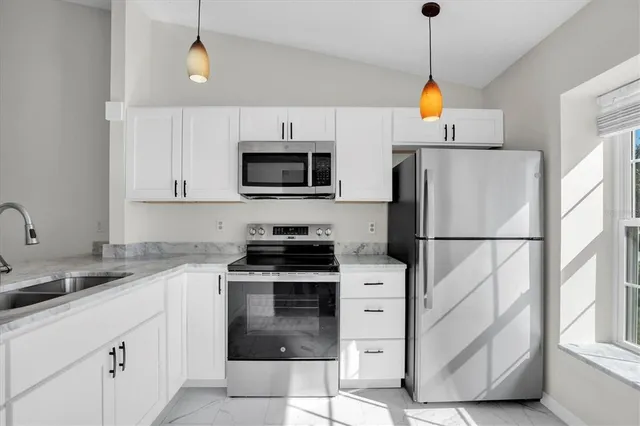 a kitchen with stainless steel appliances a stove a sink a refrigerator and a window