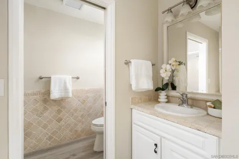 a bathroom with a granite countertop sink a toilet and a mirror