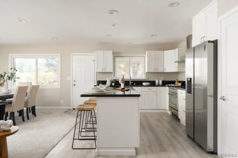 a kitchen with stainless steel appliances a refrigerator a stove a sink dishwasher and white cabinets with wooden floor