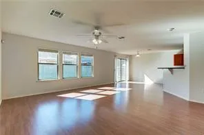 a view of an empty room with window and wooden floor