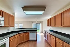 a kitchen with granite countertop a sink a stove a counter space and cabinets