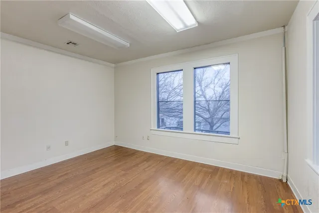 an empty room with wooden floor and windows