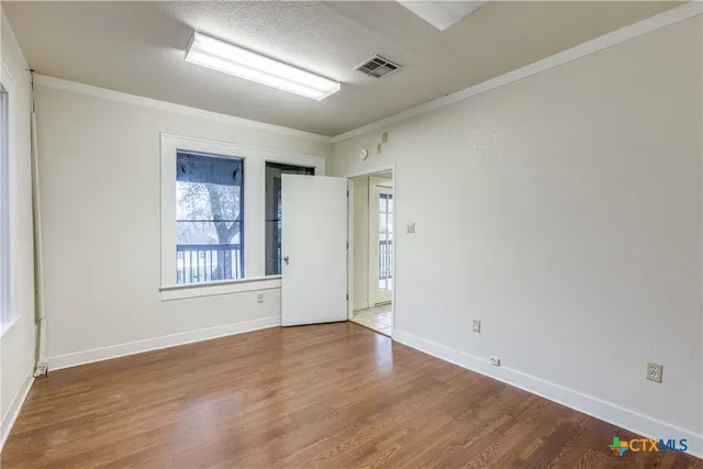 an empty room with wooden floor and windows