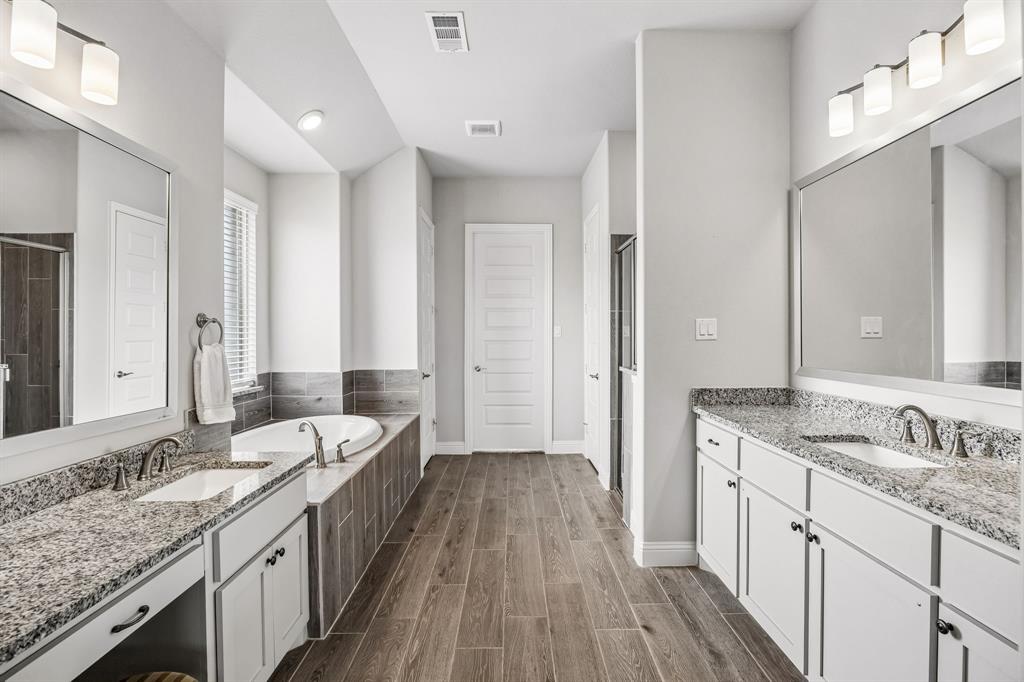 1581 Lynx Loop Forney, TX 75126 - Photo 21 of 38 Primary bath featuring two vanities, wood finish floors, a garden tub, and a walk in shower