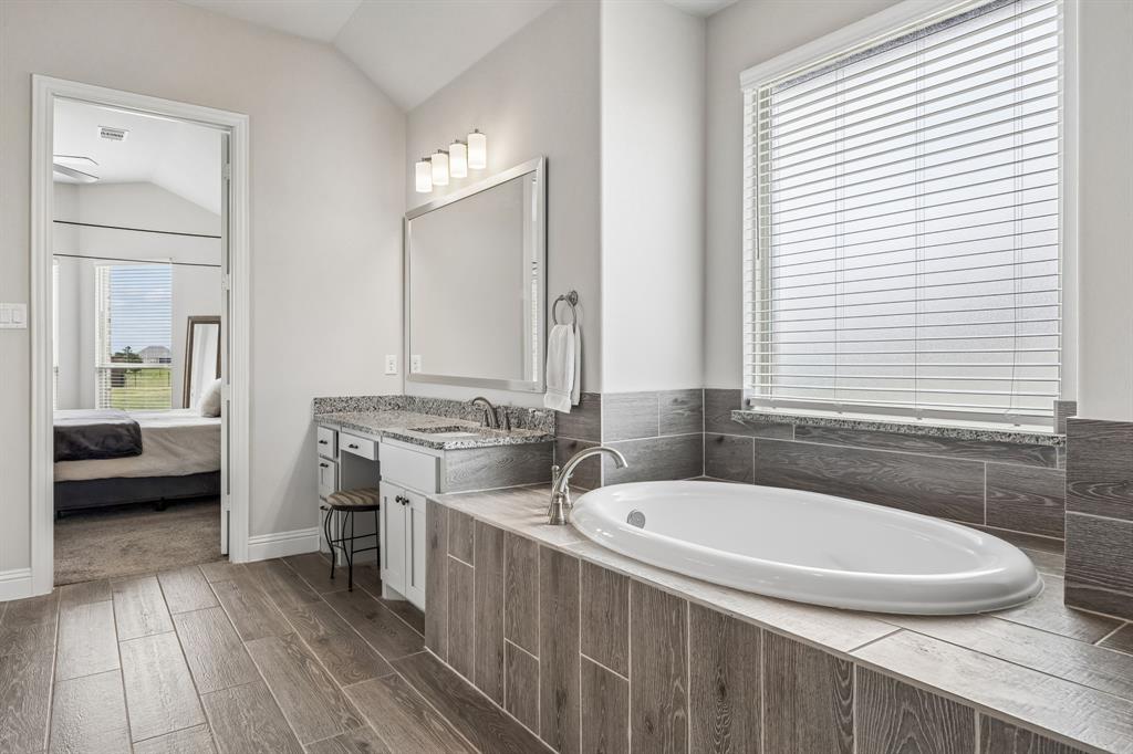 1581 Lynx Loop Forney, TX 75126 - Photo 22 of 38 Primary bath with vanity, ensuite bath, wood finish floors, a bath, and vaulted ceiling