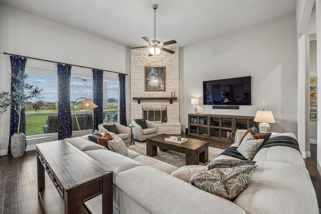 1581 Lynx Loop Forney, TX 75126 - Photo 10 of 38 Living room with a stone wood burning fireplace, ceiling fan and great view of the back yard.