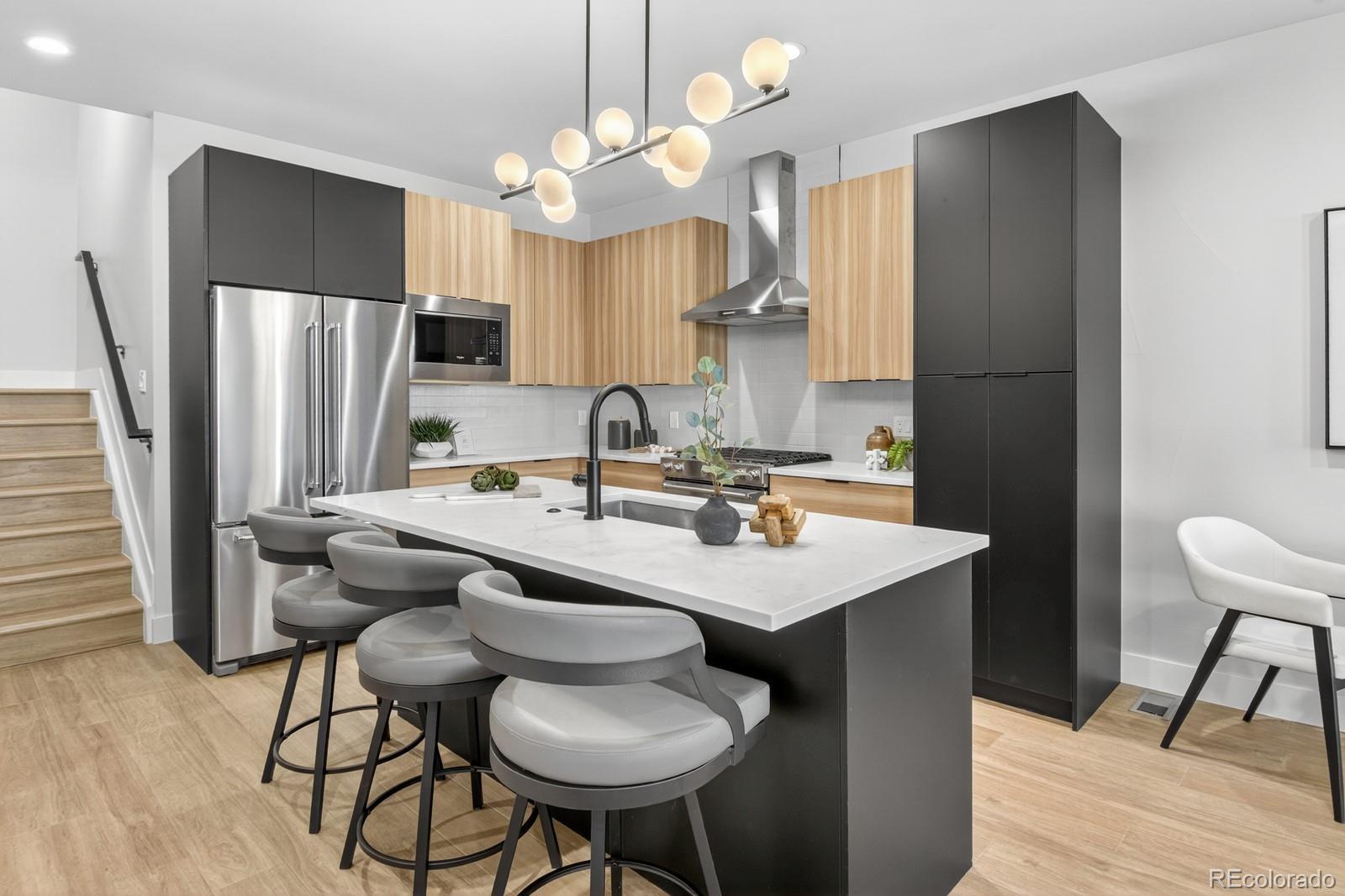 a kitchen with stainless steel appliances granite countertop a sink a stove a refrigerator and island with wooden floor