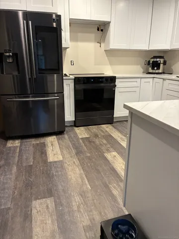 a kitchen with granite countertop a refrigerator stove and sink