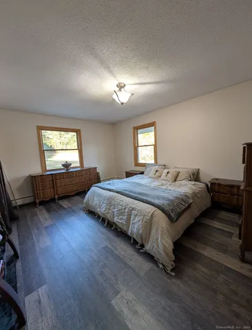 a spacious bedroom with a bed and a flat tv screen on the dresser