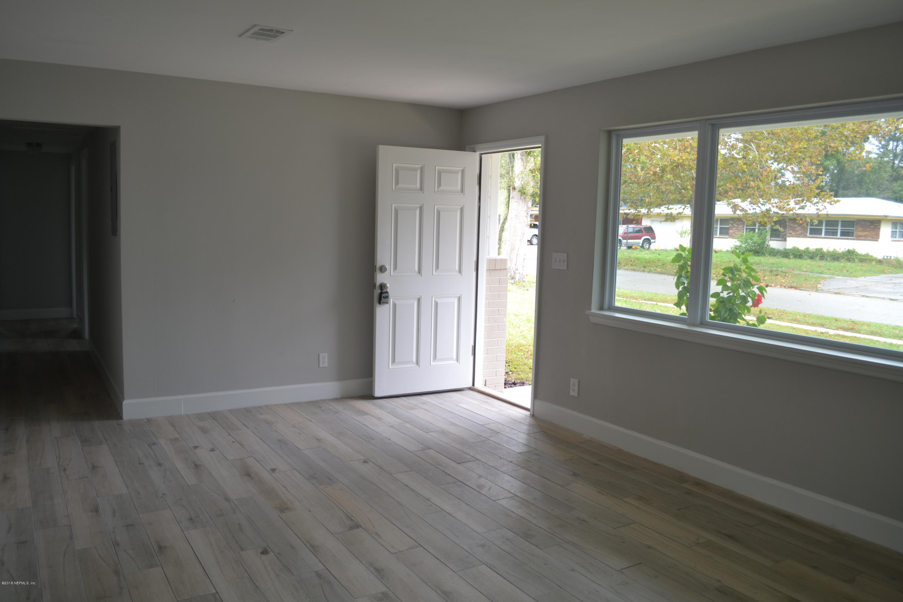 2726 Sam Road Jacksonville, FL 32216 - Photo 6 of 19 a view of an empty room with wooden floor and a window