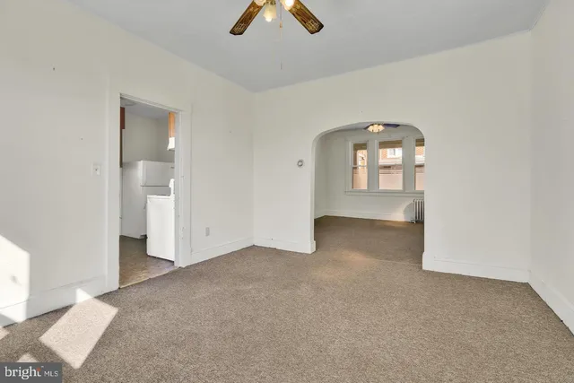 an empty room with chandelier fan and windows