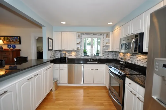a kitchen with stainless steel appliances granite countertop a stove a sink and a white refrigerator