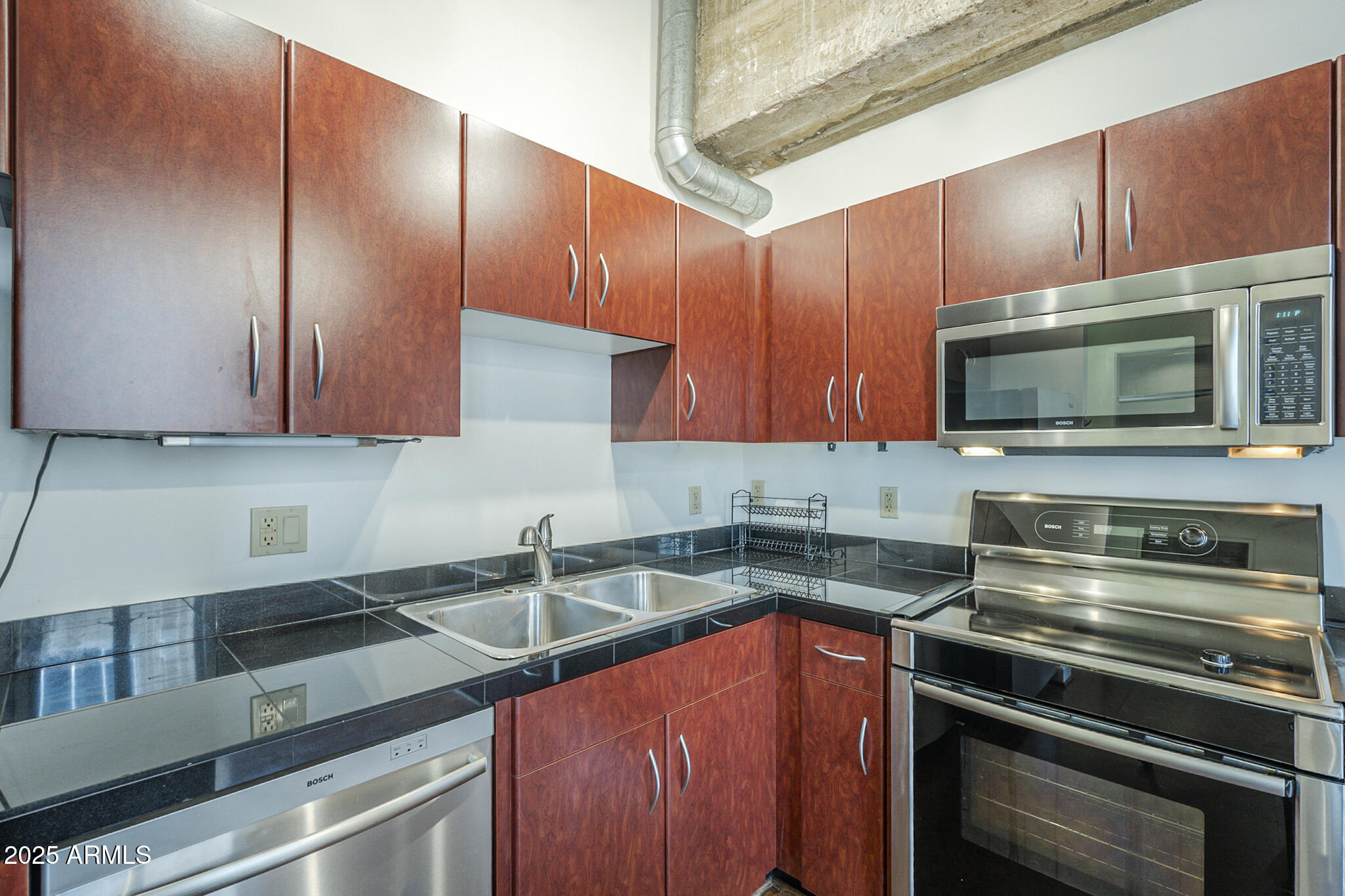 114 West Adams Street, Unit 1007 Phoenix, AZ 85003 - Photo 12 of 51 a kitchen with stainless steel appliances wooden cabinets and a stove top oven