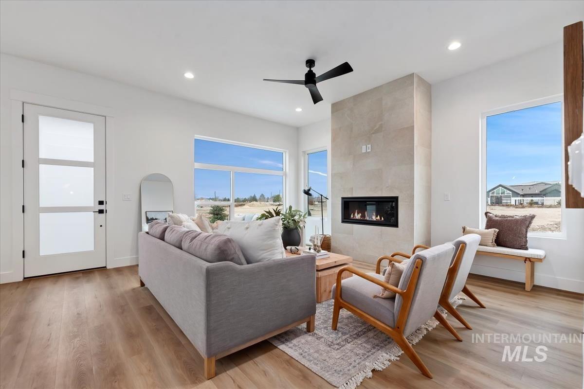 735 South Calhoun Lane Star, ID 83669 - Photo 9 of 47 Living area featuring light wood finished floors, a tiled fireplace, ceiling fan, and recessed lighting