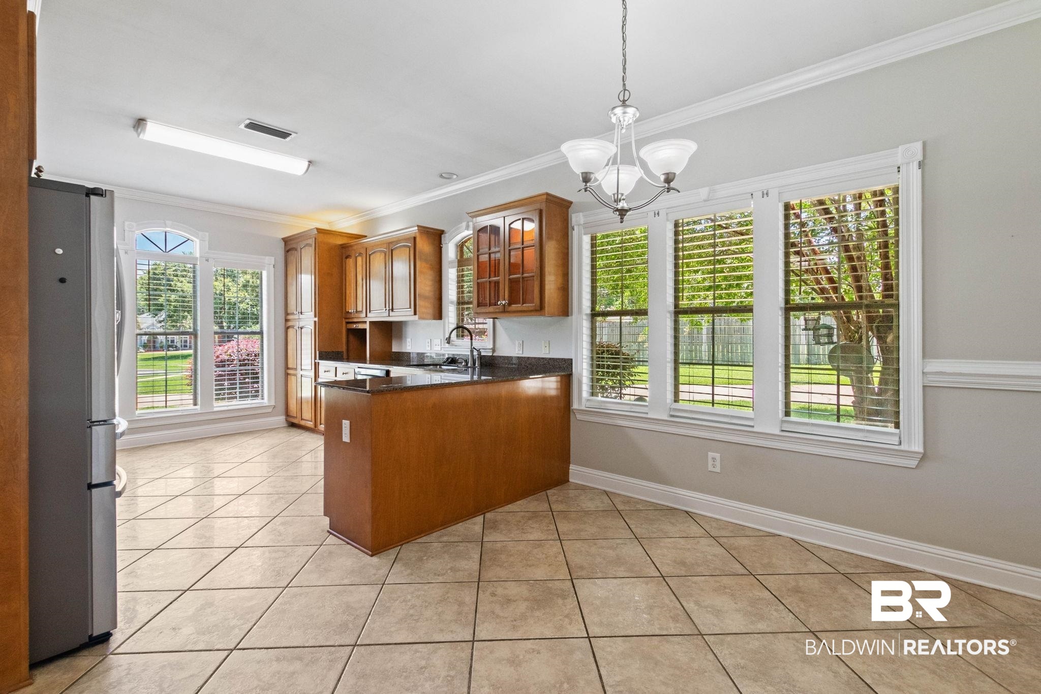 3176 Cedar Court Mobile, AL 36619 - Photo 9 of 33 Kitchen and dining area featuring tile flooring, wood cabinetry, dark countertops, and a built-in refrigerator