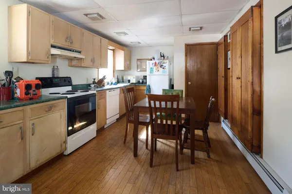 a kitchen with stainless steel appliances granite countertop wooden floors a dining table and chairs