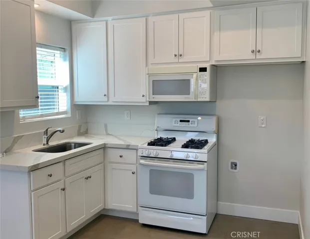 a kitchen with white cabinets and white appliances